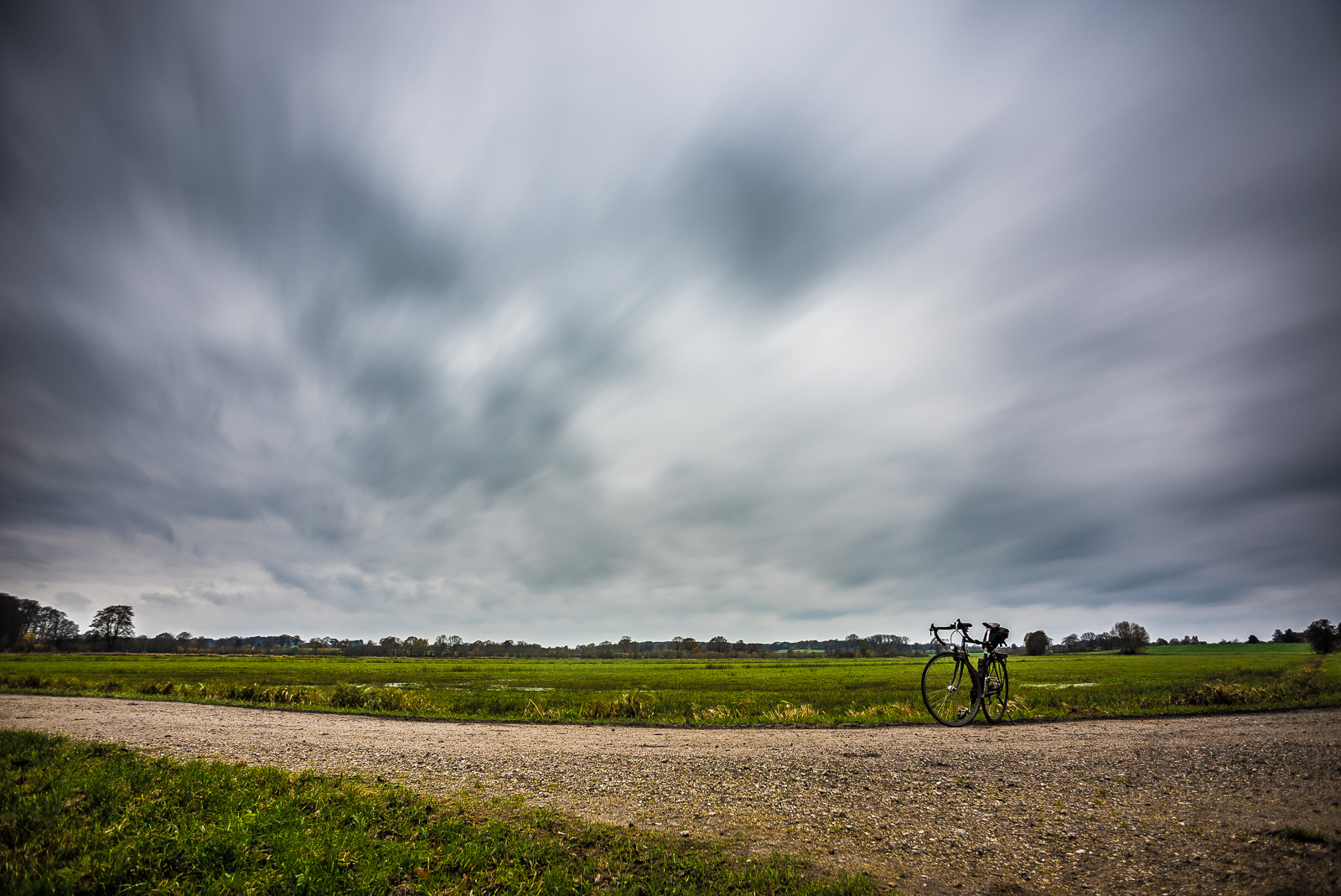 Fahrrad vor Wiese unter schnell ziehenden Wolken