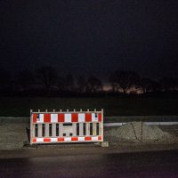 Nachtaufnahme: Baustellenabsperrung vor Bäumen