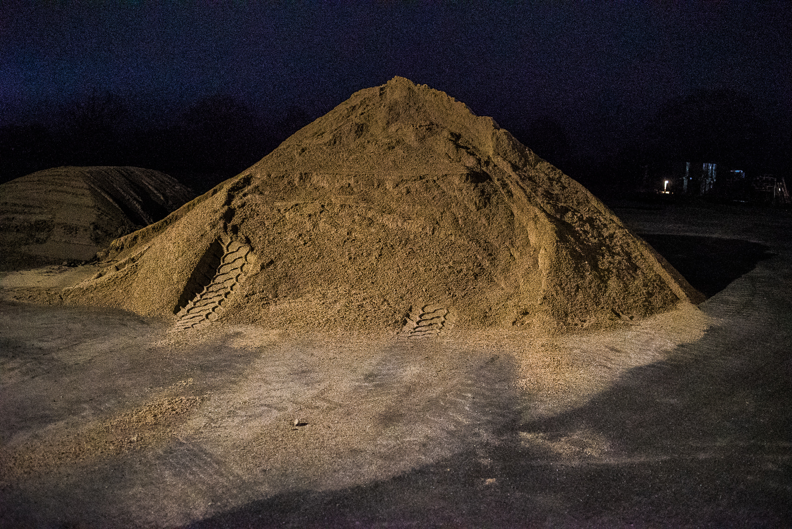 Nachtaufnahme: Riesiger Sandhaufen mit Reifenspuren