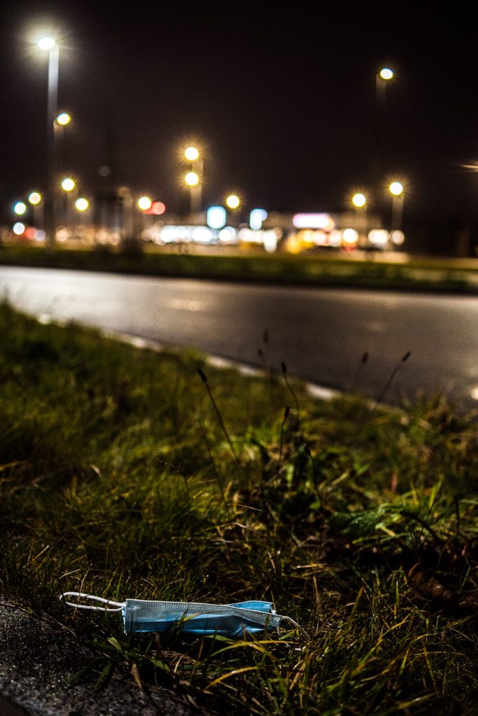 Nachtaufnahme: Eine Maske liegt am Straßenrand im Gras
