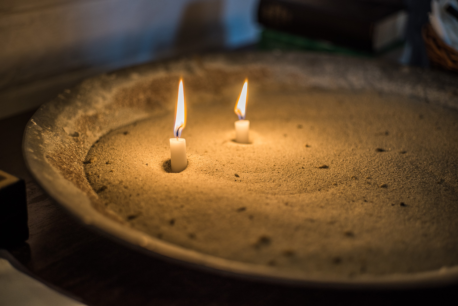zwei brennende Opfer-Kerzen in einer mit Sand gefüllten Schale