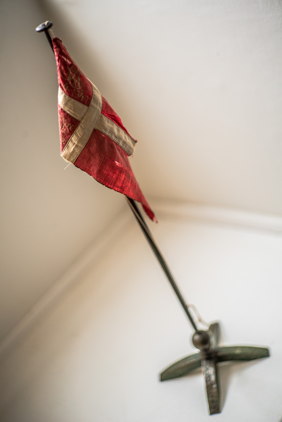 Ein kleiner dänischer Wimpel, rot mit weißen gekreuzten Balken, steht in einer weißen Raumnische