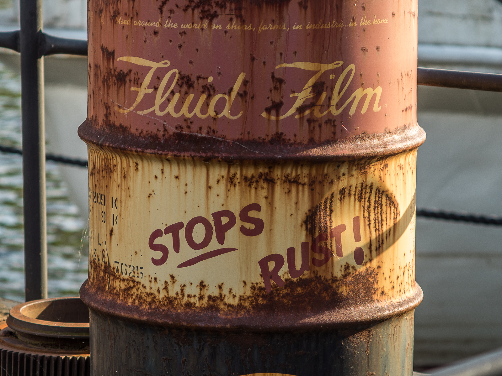 Ein altes, rostiges Fass mit der Aufschrift "Fluid Film Stops Rust!"