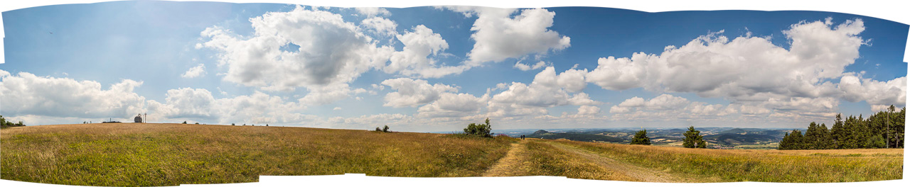 Panorama eines Feldes auf einem Berg mit Kuppel eines Flugplatzes, viele Wolken
