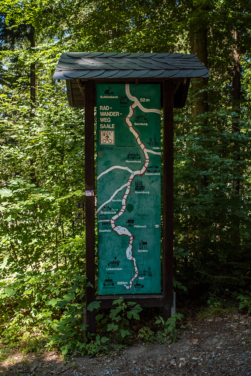 Ein altmodisch gezeichnetes Übersichtsscchild des Saale-Radwegs im Wald