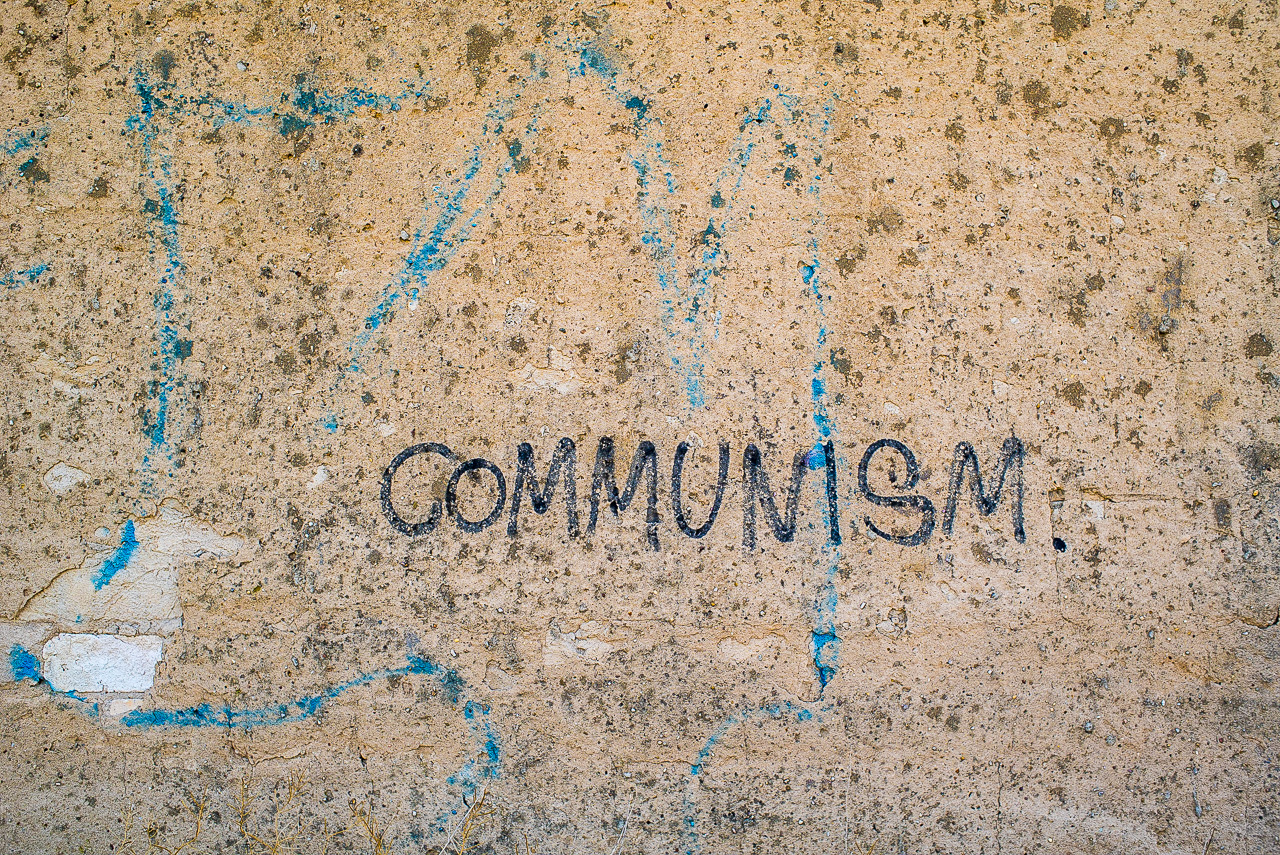 Graffito "Communism." auf einer abgeschabten Mauer