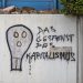 Ein Graffito an einer hell-grauen BetonWand. Ein stilisierter TotenSchädel, daneben in schmieriger Schrift "Das Gespenst des Kapitalismus"
