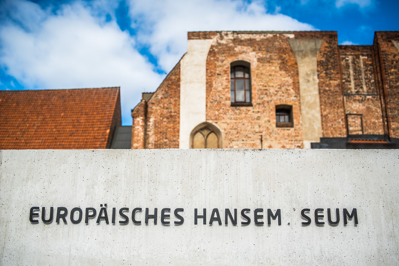Ein BacksteinGebäude mit RundBogenFenstern, davor eine helle BetonWand mit den Buchstaben "Europäisches Hansem_seum" (das u fehlt).