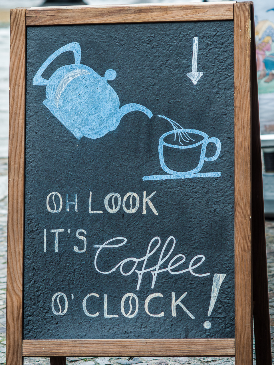 Schild ähnlich einer Schiefertafel mit aufgemalter Kanne, Tasse und Schrift "Oh look, it’s Coffee o’ Clock"