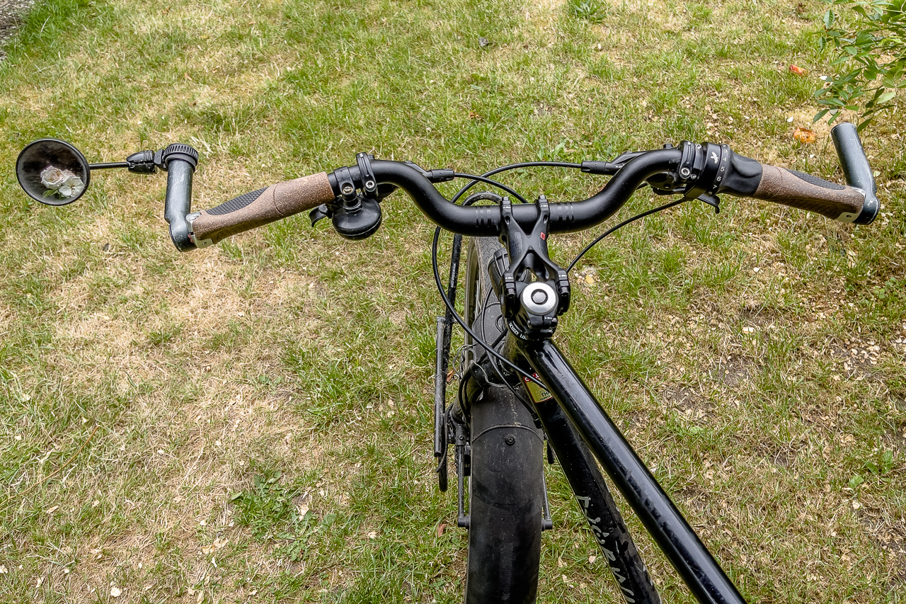 Ein leicht geschwungener FahrradLenker mit braunen Griffen