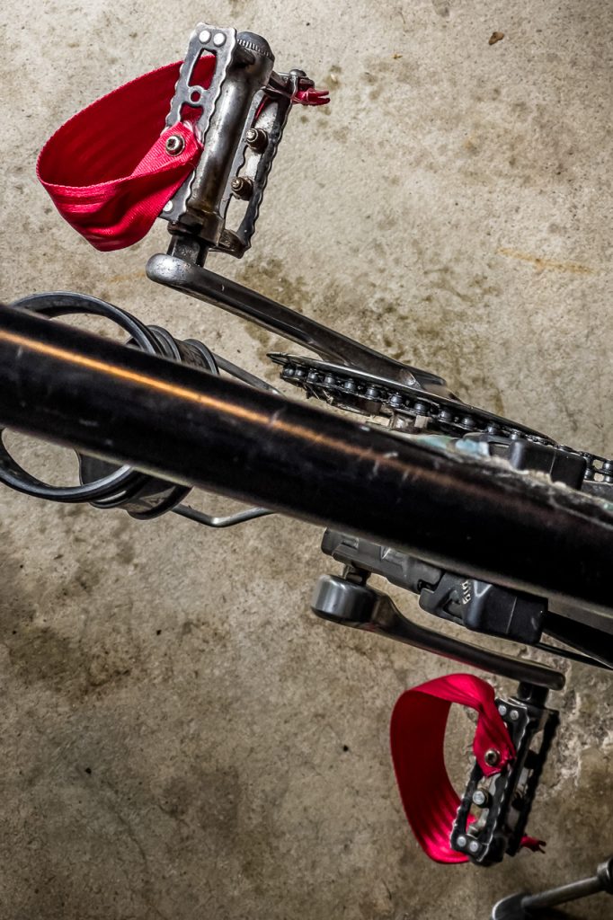 Zwei Pedale mit neuen roten GurtbandRiemen von oben, über das Oberrohr des Rades hinweg fotografiert.