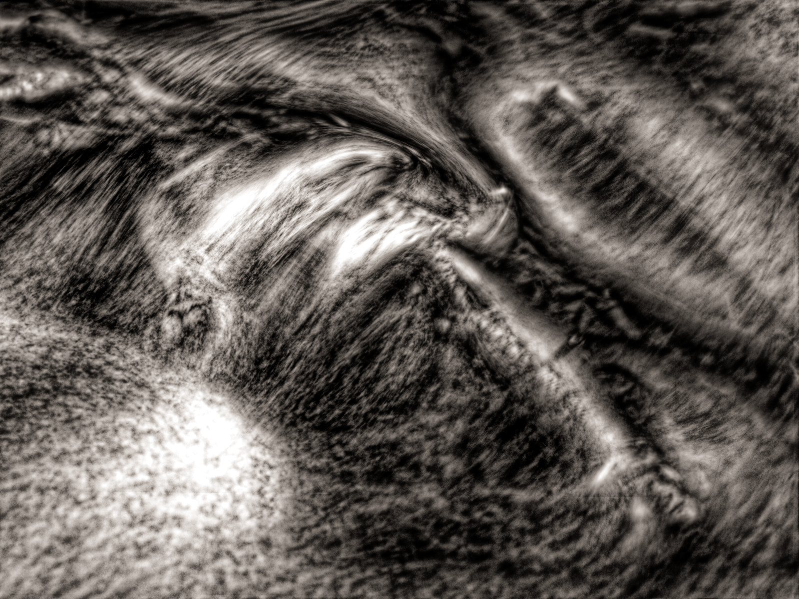 Stromschnelle in einem Bach als Detail-Foto. Sehr lange Belichtung als kontrastreiches, warm getontes Schwarz-Weiß-Foto.