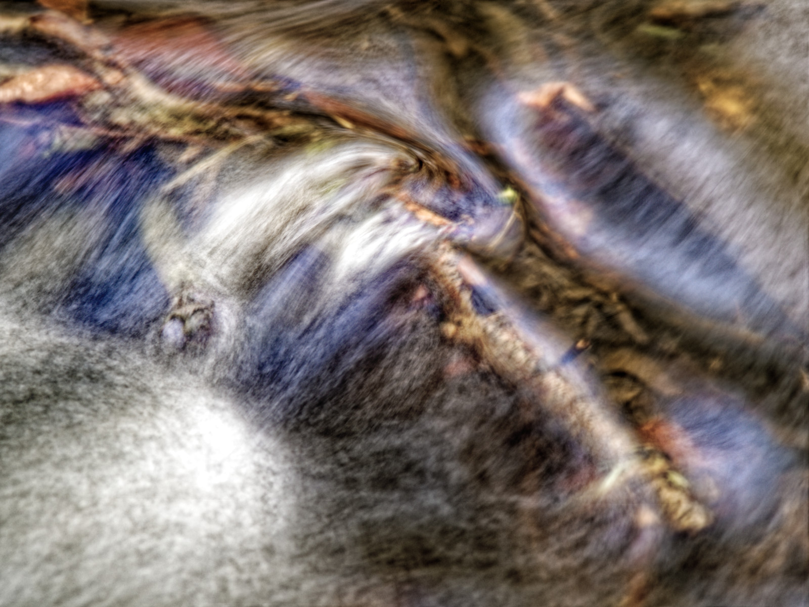 Stromschnelle in einem Bach als Detail-Foto. Sehr lang belichtet, die Wasser-Bewegung zieht sehr weiche Spuren.