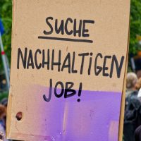 Papp-Plakat, mit der Hand beschrieben: "Suche nachhaltigen Job!"